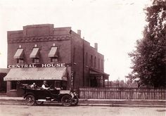 an old black and white photo of people in a horse drawn carriage outside the central house