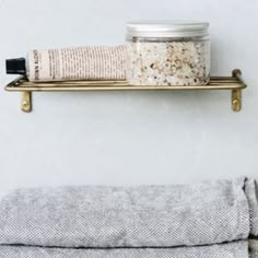 a bathroom shelf with a jar and towel on it next to a rolled up cloth