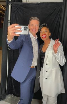 a man and woman taking a selfie in front of a black backdrop with a camera