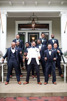 a group of men in tuxedos posing for a photo on the front steps of a house