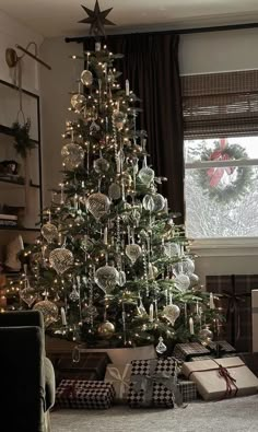 a christmas tree with presents under it in front of a window