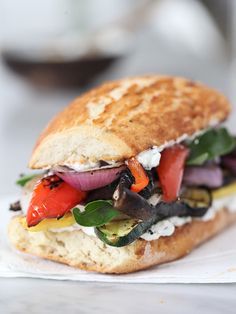 a close up of a sandwich on a napkin with tomatoes, peppers and other vegetables