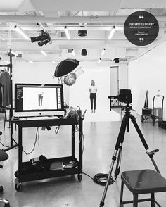 a black and white photo of an empty studio with equipment in the foreground, two men standing behind them