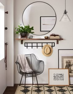 there is a chair and some pictures on the wall in this room with a round mirror above it