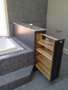 a bath tub sitting next to a wooden cabinet in a room with tile floors and walls