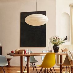 a dining room table with chairs and a large painting on the wall above it,