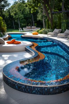 an outdoor swimming pool surrounded by white lounge chairs and orange pillows on the side of it