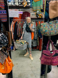 an older woman is looking at her cell phone in the mirror while she shops for handbags and purses