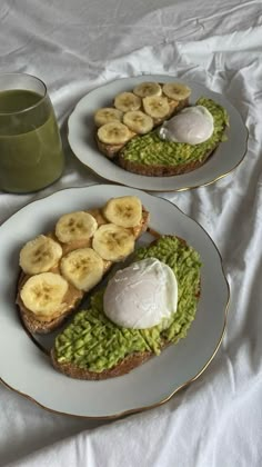 two white plates topped with toast covered in avocado and banana slices