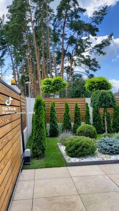 an outdoor garden with wooden fence and green plants on the side of the building, surrounded by wood slats