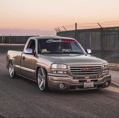 a silver truck parked on the side of a road next to a fence and barbed wire