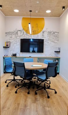 a conference room with blue chairs and a flat screen tv mounted on the wall above it