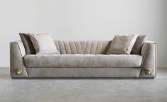 a couch with two pillows on it in front of a white wall and flooring