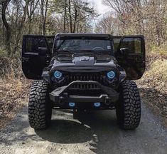 the jeep is parked on the side of the road in front of some trees and bushes