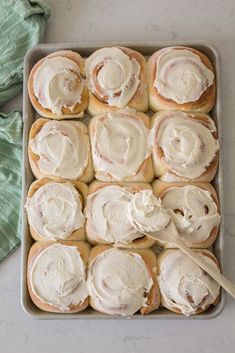 a pan filled with cinnamon rolls covered in frosting