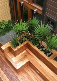 an elevated wooden planter with plants in it on a deck next to a building