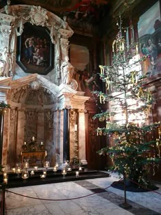 a christmas tree in the middle of a room with paintings on the walls and ceiling