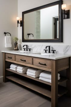 a bathroom with two sinks and a large mirror over it's counter top that has folded white towels on it