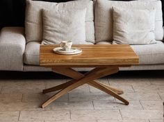 a wooden table sitting on top of a white couch next to a coffee cup and saucer