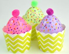 three cupcakes decorated with colorful sprinkles and pom - poms