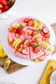 a strawberry cake with sliced strawberries and lemons on top, next to a bowl of strawberries