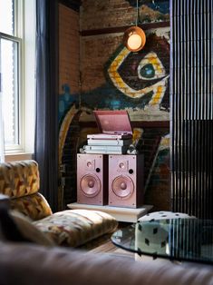 a living room filled with furniture and a painting on the wall above it's speakers