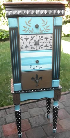 an old dresser is painted blue and has polka dots on the bottom, with black trim