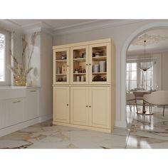 a kitchen with white cabinets and marble flooring next to a dining room table in the background