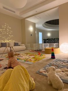 a baby sitting on the floor next to a white dog