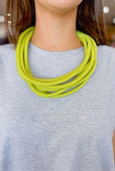 a woman wearing a yellow necklace and grey shirt