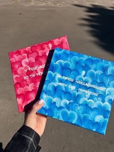 two handmade greeting cards with blue and red swirls on them, one being held by a person