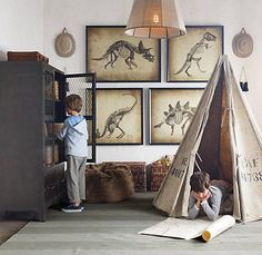 there is a child playing in a teepee with dinosaur pictures on the wall behind it