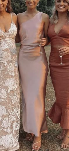 three women standing next to each other holding wine glasses