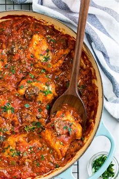 a large pot filled with meatballs covered in sauce and garnished with parsley