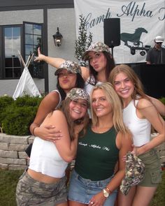 a group of young women standing next to each other in front of a building with a banner behind them