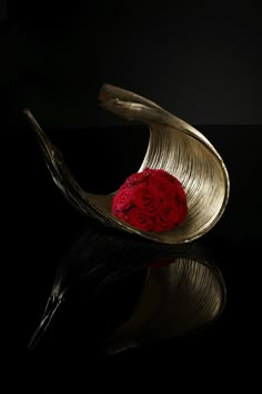 a red rose sitting on top of a metal object in the dark with water reflection