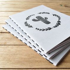 a stack of white notebooks sitting on top of a wooden table next to each other