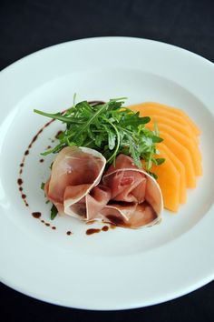 a white plate topped with meat and veggies on top of a black table