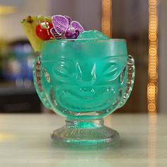 a green glass bowl filled with fruit and veggies on top of a counter