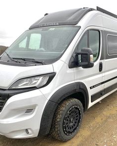 a white van parked on top of a dirt field