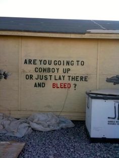 a sign on the side of a building that says, are you going to cowboy up or just lay there and bleed?