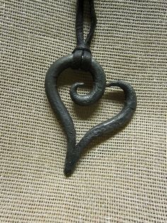 a heart shaped metal object hanging from a string on a burlock cloth background