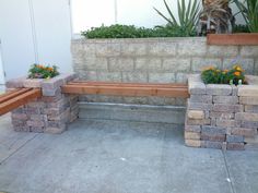 two planters with flowers are next to a stone bench