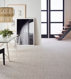 a dining room with white walls and beige carpeting, stairs leading up to the second floor