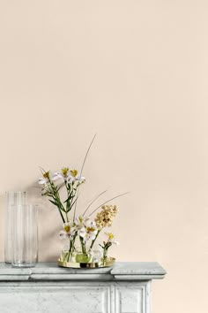 vases with flowers sit on top of a marbled table in front of a pink wall