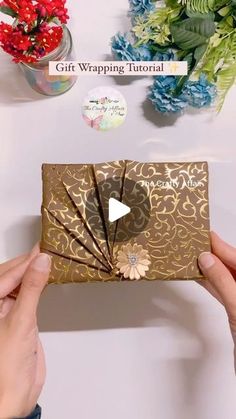 someone is holding up a gift wrapper that has been folded into the shape of a flower