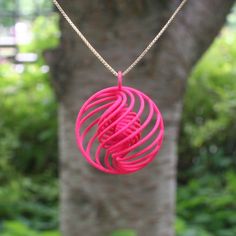 a pink necklace is hanging from a tree