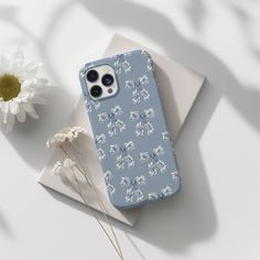 an iphone case sitting on top of a table next to a flower