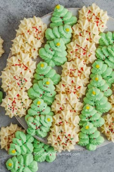 green and white decorated cookies on a plate with sprinkles in the shape of christmas trees