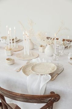 the table is set with white dishes and candles